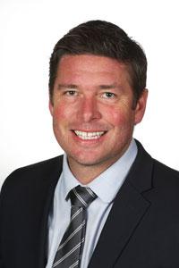 Smiling man in a suit and tie on a white background.